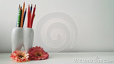 Enlarged photo of tooth-shaped pencil holder with colored pencils. Stock Photo