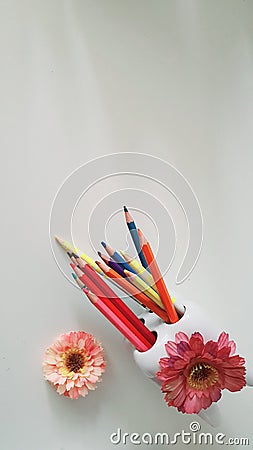 Enlarged photo of tooth-shaped pencil holder with colored pencils and flowers. Stock Photo