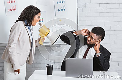 Enraged female boss with loudspeaker yelling at subordinate in company office Stock Photo