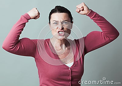 Enraged 40s woman flexing her muscles up for metaphor Stock Photo