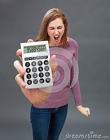 Enraged young woman screaming against financial economy on oversized calculator Stock Photo