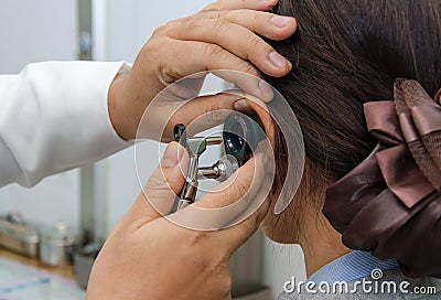 ENT physician checking patient's ear using otoscope with an inst Stock Photo