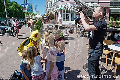 Entertainer playing with happy kids during children protection day while photographer takes photos Editorial Stock Photo