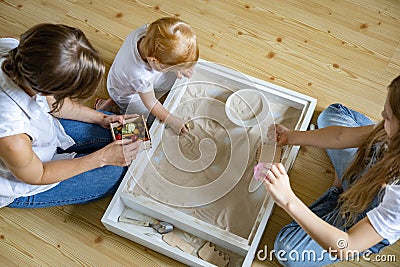 Enthusiastic family playing home kinetic sandbox use wooden ecological toys enjoying leisure Stock Photo