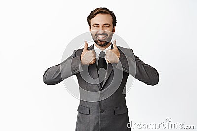 Enthusiastic male boss in suit, showing thumbs up satisfied. Pleased businessman recommending something, like and Stock Photo