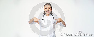 Enthusiastic medical staff, asian female healthcare worker, pointing fingers down and smiling amazed, showing discounts Stock Photo