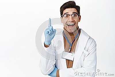 Enthusiastic medical worker in glasses and gloves, raising finger up and smiling, pitching an idea, doctor suggesting Stock Photo