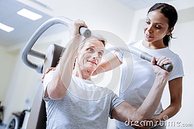 Enthusiastic pensioner using exercise equipment in a rehabilitation center Stock Photo
