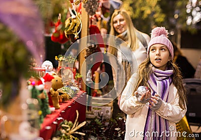 Enthusiastic teenager girl picking tree decorations at street market Stock Photo