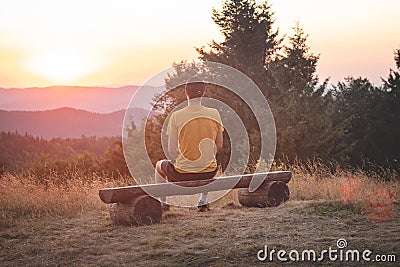 Enthusiastic traveler sits on a wooden bench and watches the last remnants of sunshine in the raw nature. Sunset on Horni Becva, Stock Photo