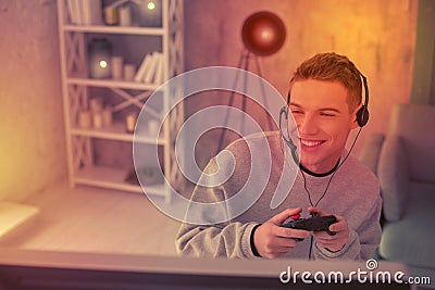 Enthusiastic young fellow using gamepad for videogame Stock Photo