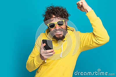 Enthusiastic young man holding fist up in the air and smiling Stock Photo