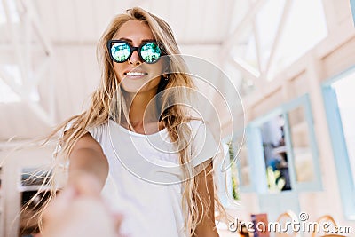 Enthusiastic young woman fooling around in cafeteria. Lovely tanned girl in sunglasses posing emoti Stock Photo