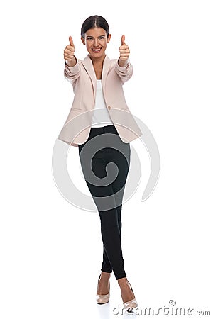 Enthusiastic young woman in pink jacket making thumbs up gesture Stock Photo