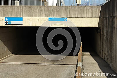 Entrance of a concrete road underpass with traffic directional arrow signs on the upper side. Stock Photo