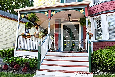 Entrance of old ornate gingerbread victorian style house decorated for summer with flowers and porch decor Stock Photo