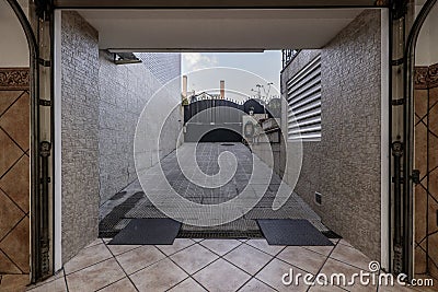 Entrance portal to a garage of a single-family home with access ramp and gate with folding metal doors Stock Photo