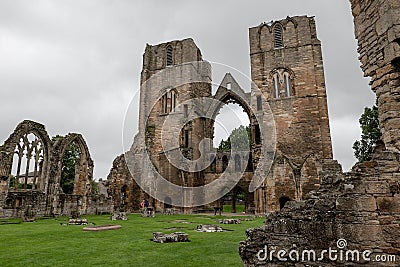 The entrance, ruin of main wall and courtyard of Elgin Cathedral with tourists in Scottish cloudy weather Editorial Stock Photo