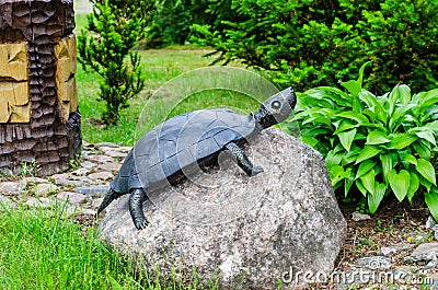 A turtle made of metal stands on a stone at the entrance to the park Editorial Stock Photo