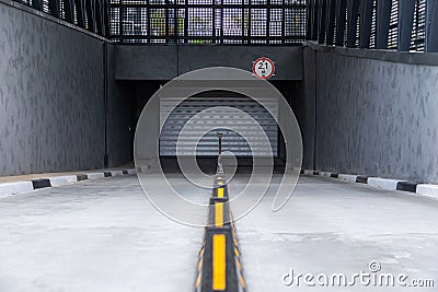 Entrance to underground parking space with roller-shutter door and road dividers Stock Photo