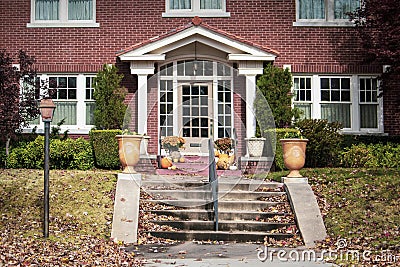 Entrance of two story upscale brick house in autumn with steps and pole laturn and pillared porch with attractive paned front door Stock Photo