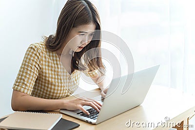 Entrepreneur concept a young female freelancer working on her laptop device typing an urgent document seriously Stock Photo