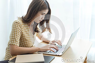 Entrepreneur concept a young female freelancer working on her laptop device typing an urgent document seriously Stock Photo