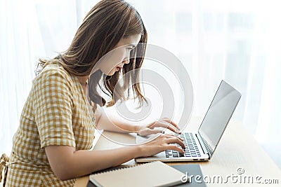 Entrepreneur concept a young female freelancer working on her laptop device typing an urgent document seriously Stock Photo