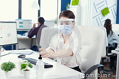 Entrepreneur wearing face mask and face shield using gel for hand hygine Stock Photo