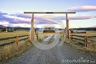 Entry gate to a nice wooden ranch home with beautiful landscape. Stock Photo