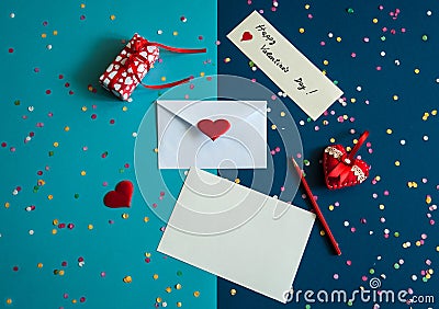 An envelope, a blank sheet of paper, a pencil, a gift box, a hand-sewn heart with ribbons and lace, a scattering of colored confet Stock Photo