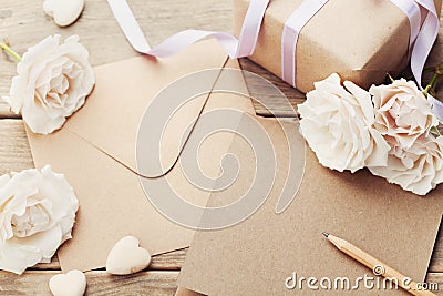 Envelope or letter, gift, paper card and vintage rose flowers on rustic wooden table for greeting on Mother or Woman Day. Stock Photo