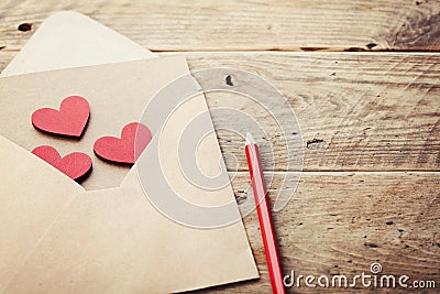 Envelope or letter and red hearts on rustic table for love message on Valentines Day in retro toning. Stock Photo