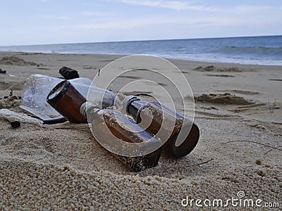 Glass bottles and plastic bottles discarded by the beautiful seaside are indigestible waste. Stock Photo
