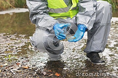 An environmental laboratory specialist in a protective suit lids a glass container with a soil sample for research Stock Photo