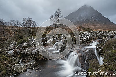 Epic landscape image of Buachaille Etive Mor waterfall in Scottish highlands on a Winter morning with long exposure for smooth Stock Photo