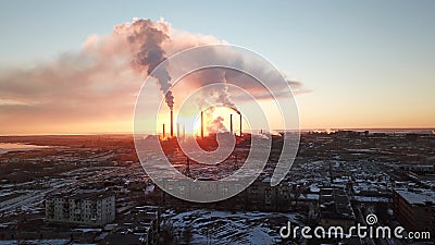 Epic sunset on the background of a Smoking factory. The red sun with bright rays goes beyond the pipe factories and smog. Stock Photo