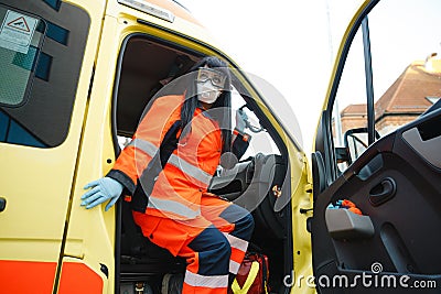 Epic superhero shot: Serious female paramedic sits at ambulance vehicle ready for action Stock Photo