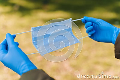 Epidemiological methods of prevention for protection from sars cov 2. Medical mask in hands. Blue sterile gloves Stock Photo