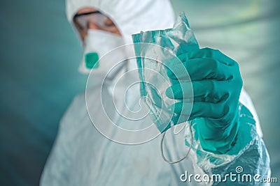 Epidemiologist holding respiratory mask with blood stains Stock Photo