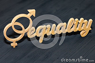 EQUALITY word carved out of plywood. Symbol of gender equality. Black wooden background Stock Photo