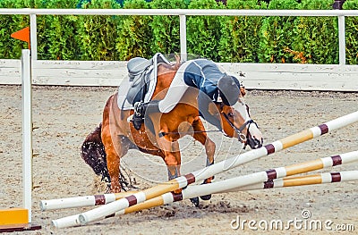 Young rider falling from horse during a competition. Horse show jumping accident. Stock Photo