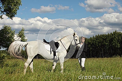 Equestrian woman in riding clothes galloping white purebred Stock Photo