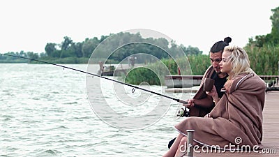 Equipaggi abbracciare la sua donna adorabile alla mattina fredda vicino al fiume, coppia che si siede con la barretta sul bacino video d archivio Equipaggi abbracciare la sua donna adorabile alla mattina fredda vicino al fiume, coppia che si siede con la barretta sul bacino video d archivio