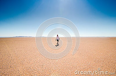 Erg Chigaga, Morocco - October 09, 2013. Man in hat walking on dry lake Iriki in Sahara Desert Editorial Stock Photo