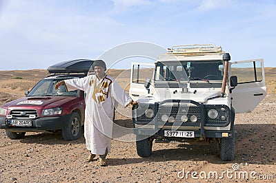 ERG CHIGAGA, MOROCCO - OCTOBER 21 2020: Tourists cars and the moroccan guide in the desert, Africa. Editorial Stock Photo