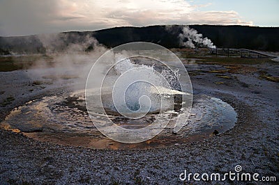 Erupting geyser: clouds reflected in a pond of hot spring run-off surrounded by white hydrothermal crust. Stock Photo