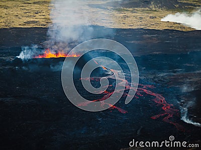 Erupting volcano, lava pouring out into a devastated surrounding, drone shot Stock Photo