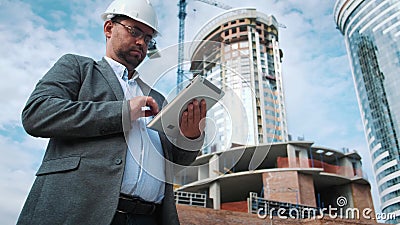Erwachsener Ingenieur oder Architekt benutzt eine Tablette in Kraft Schreibt eine Mitteilung oder überprüft eine Zeichnung Gegen stock footage Erwachsener Ingenieur oder Architekt benutzt eine Tablette in Kraft Schreibt eine Mitteilung oder überprüft eine Zeichnung Gegen stock footage