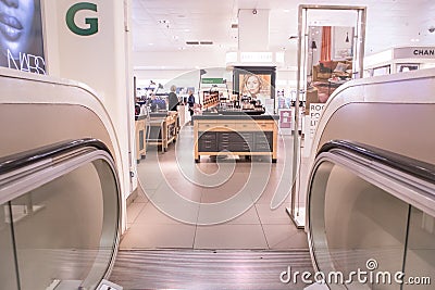 Escalator exit inside a modern department store exiting to make up cosmetics clothing department Editorial Stock Photo